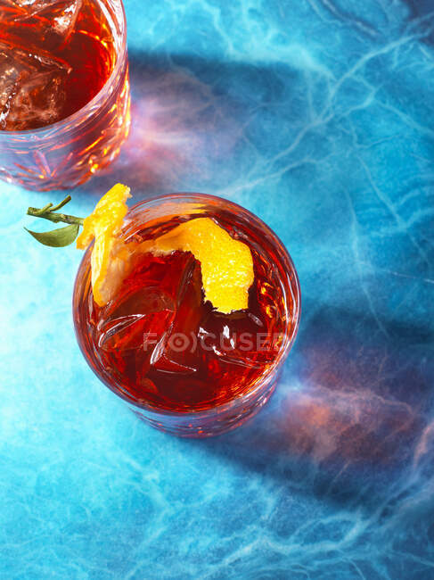 Negroni cocktails with lemon zest on blue surface — Stock Photo