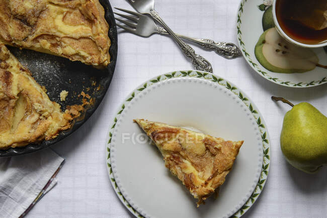 Fetta di un mascarpone e una crostata di pera, pere verdi, tazza di tè — Foto stock