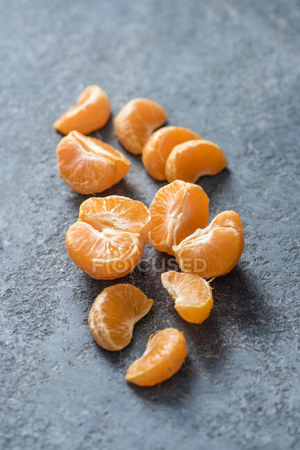 Pieces of peeled mandarin on stone surface — Stock Photo