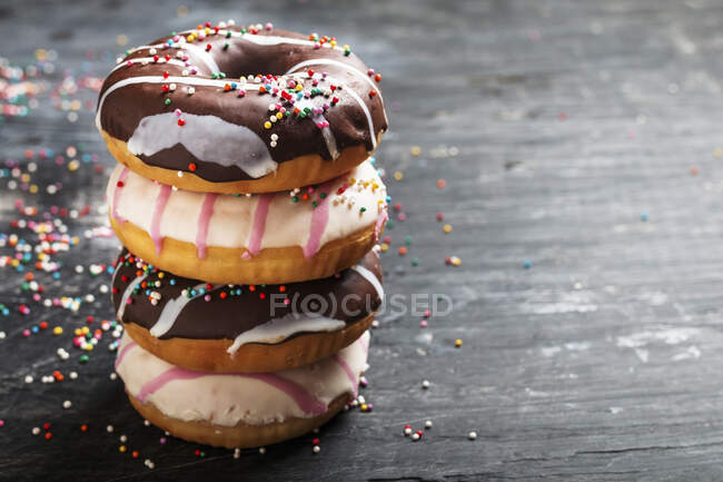 Pilha de deliciosos donuts no fundo preto — Fotografia de Stock