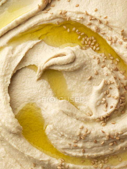 Hummus remolino con aceite de oliva y semillas de sésamo - foto de stock