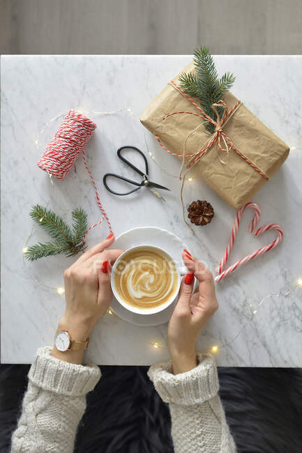 Eine Frau mit einer Tasse Kaffee in der Hand, einem Marmortisch und Kaffee — Stockfoto