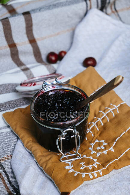 Jam in glass jar on fabric pillow — Stock Photo