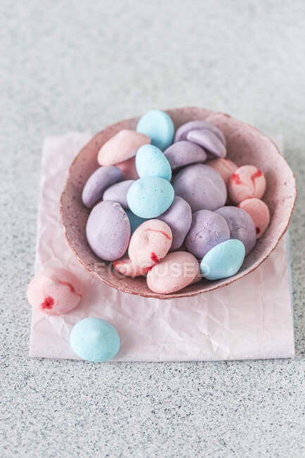 Colorful meringues in bowl and on pink napkin — Stock Photo