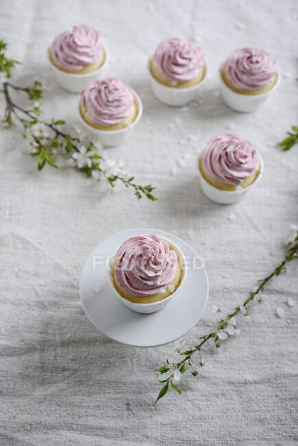 Vegan baunilha e semolina cupcakes com cobertura de framboesa, ramos com flores na mesa — Fotografia de Stock