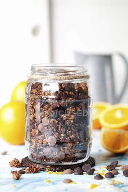 Choocolate orange granola in a jar with fresh oranges — Stock Photo
