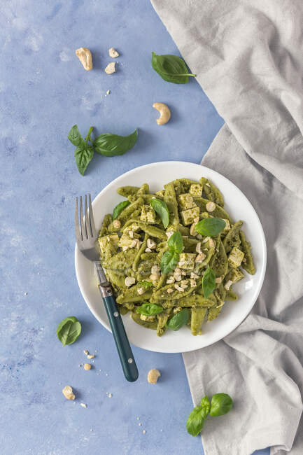 Pasta verde con pesto, tofu y hojas de albahaca - foto de stock