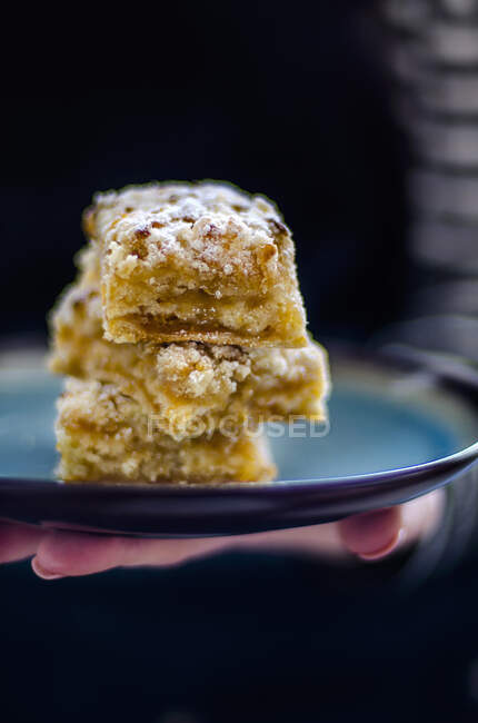 A hand holding three slices of apple crumble cake on a tray — Stock Photo