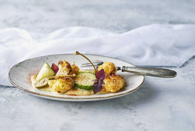 Roasted cauliflower with cauliflower almond puree with pickled cucumber, apple capers, spring onions and red cress — Stock Photo