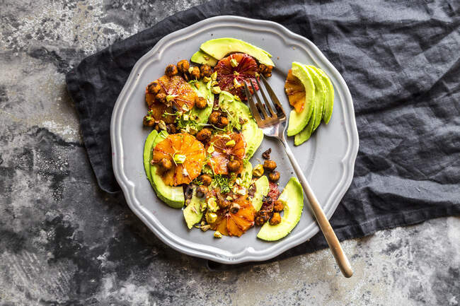 Salad of avocado, blood orange, roasted chickpeas, pistachios and cress — Stock Photo