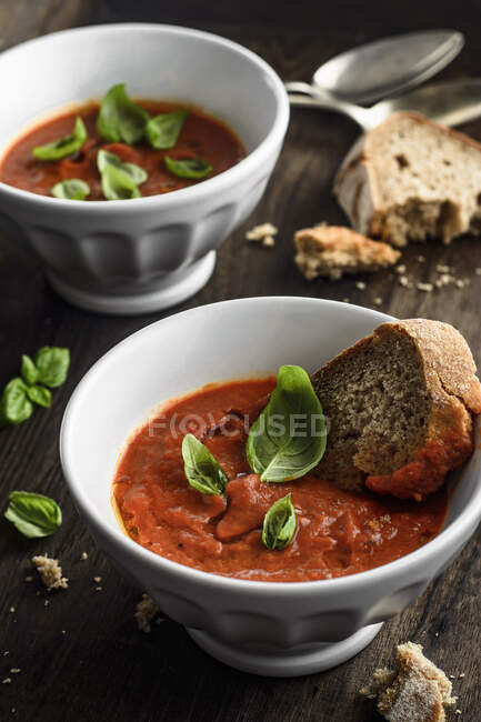 Roasted tomatoes cream soup with basil and slice of bread — Stock Photo