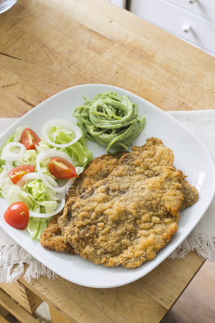 Breaded schnitzel with salad and herb spaghetti — Stock Photo
