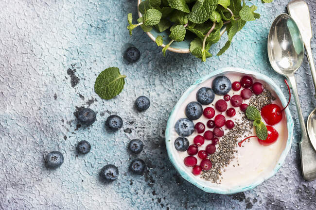 Light greek yogurt dessert with chia seeds, goji, mint leaves and fresh berries — Stock Photo