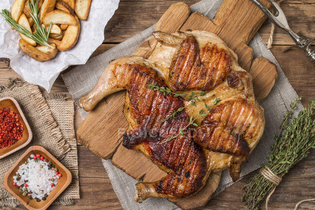 Grilled fried roast Chicken tobacco on cutting board with potatoes on wooden background — Stock Photo