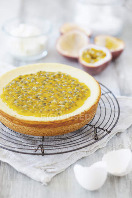 Cheesecake con frutto della passione su una griglia metallica e vari ingredienti di cottura — Foto stock