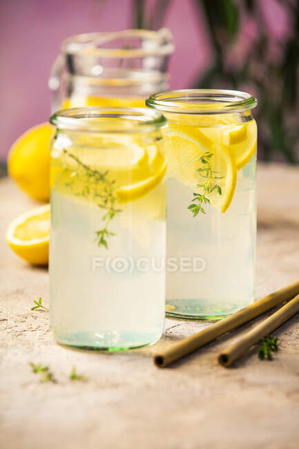 Limonada con limones y tomillo sobre mesa rústica - foto de stock