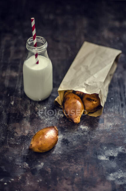 Pierogi cuit au four dans un sac en papier à côté d'une bouteille de lait — Photo de stock