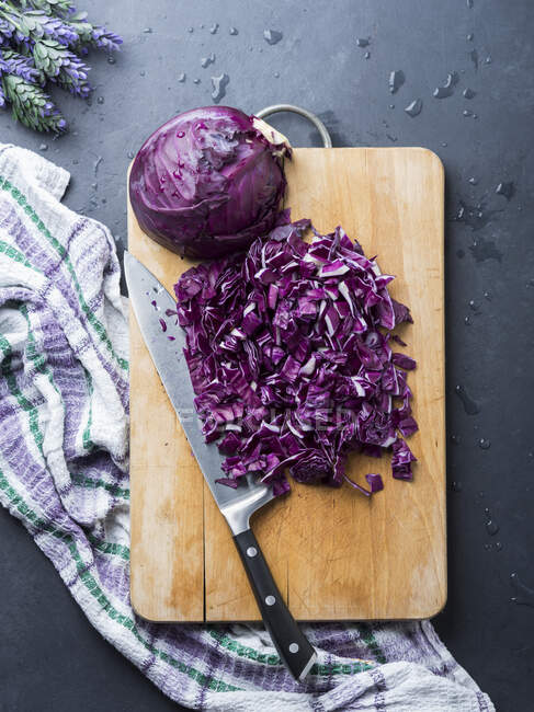 Cutting purple cabbage on wooden board — Stock Photo