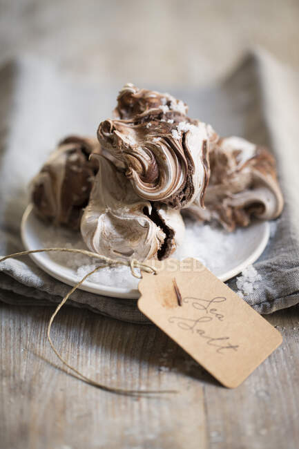 Marbled chocolate and white meringues and sea salt lettering paper tag — Stock Photo