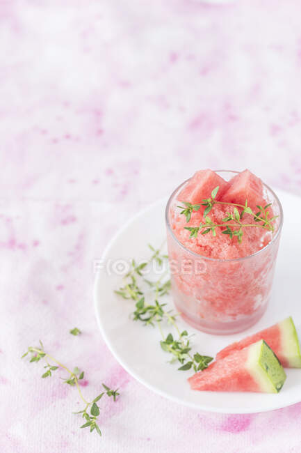Watermelon thyme granita in glass with fresh watermelon slices and herbs on plate — Stock Photo