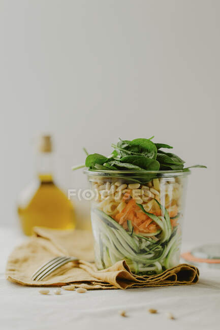 Una ensalada en capas con verduras y un aderezo de yogur en un vaso - foto de stock