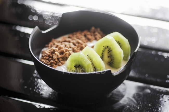 Yogurt with granola and kiwi in a black bowl — Stock Photo
