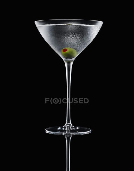 Martini com azeitona recheada em vidro sobre fundo escuro — Fotografia de Stock