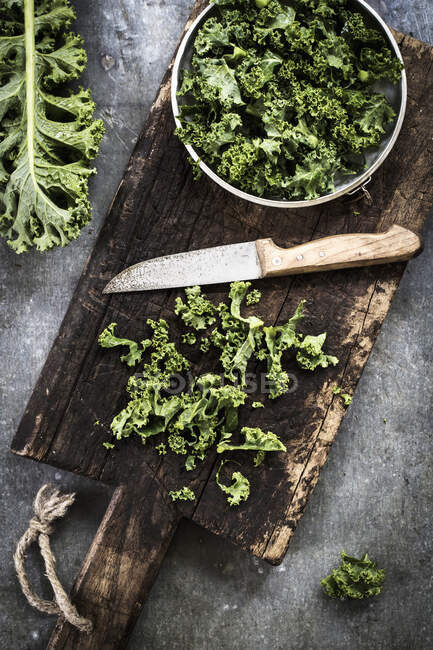 Kale on an old chopping board with a knife — Stock Photo