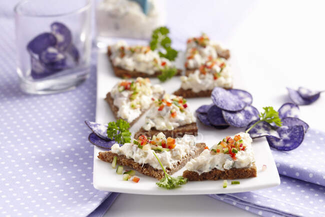 Wholemeal carnival snacks with soused herring cream and blue crisps — Stock Photo