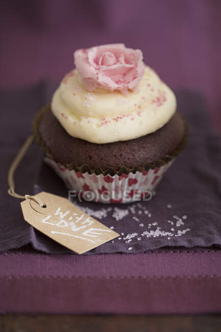 A chocolate cupcake with vanilla cream and a sugar rose — Stock Photo