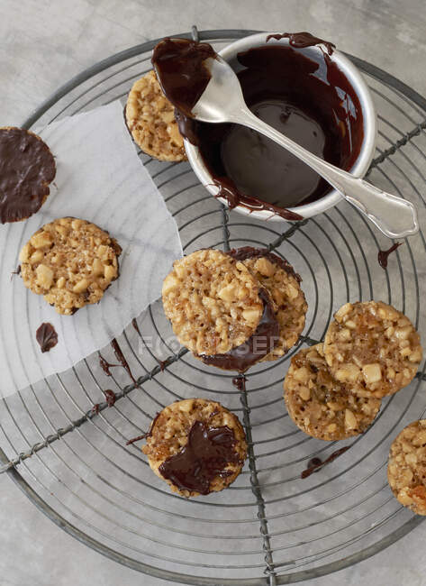 Macadamia biscuits with chocolate glaze on cooling rack — Stock Photo