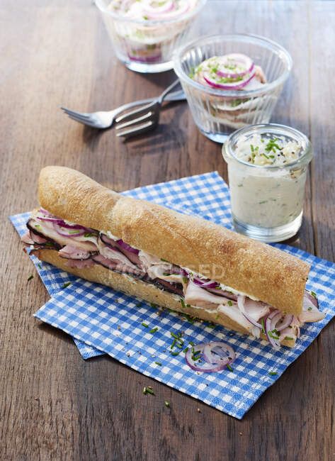 A baguette sandwich with ham, chive cream and meat salad in a jar — Stock Photo