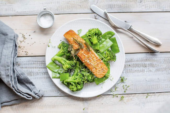 Salmon on a bed of green vegetables with mange tout - foto de stock