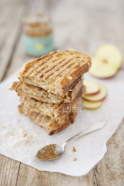 A grilled cheese sandwich made with onion bread, caramel mustard and apples on parchment paper (New York) — Stock Photo