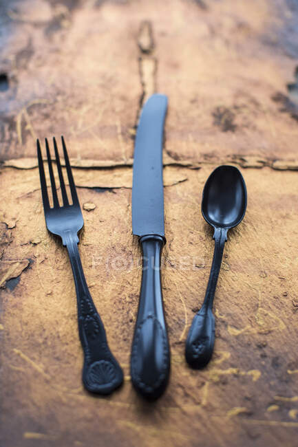 Black vintage knife fork and spoon on a copper slate — Stock Photo