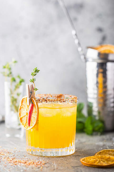 Cocktail rinfrescante di agrumi estivi con arancia, succo di limone e ghiaccio in un bicchiere su sfondo grigio — Foto stock