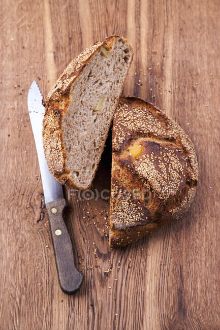 Pão de batata cortado pela metade com faca na superfície de madeira — Fotografia de Stock
