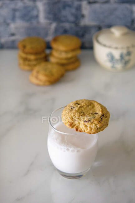 Vaso de leche con galletas y galletas apiladas sobre fondo desenfocado - foto de stock