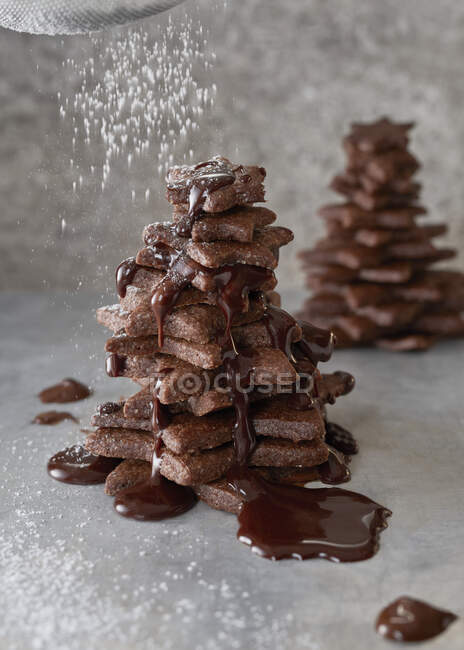 Galletas de chocolate árboles con azúcar en polvo que cae - foto de stock