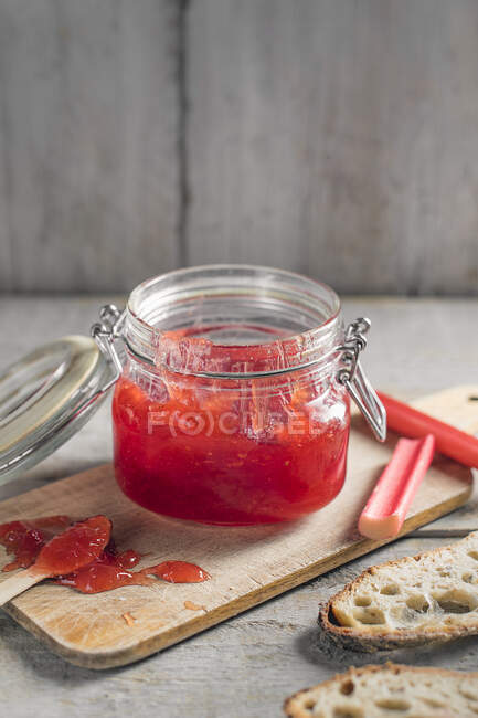 Homemade rhubarb jam in jar on wooden board — Stock Photo