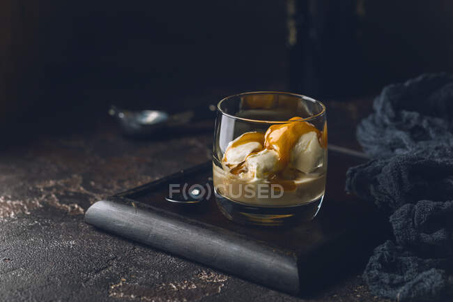 Ice cream with caramel topping and Irish cream liqueur in a glass over dark background — Stock Photo