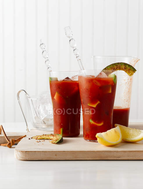 Bevande Bloody Mary con avocado in bicchieri e limone tagliato su tavola di legno — Foto stock