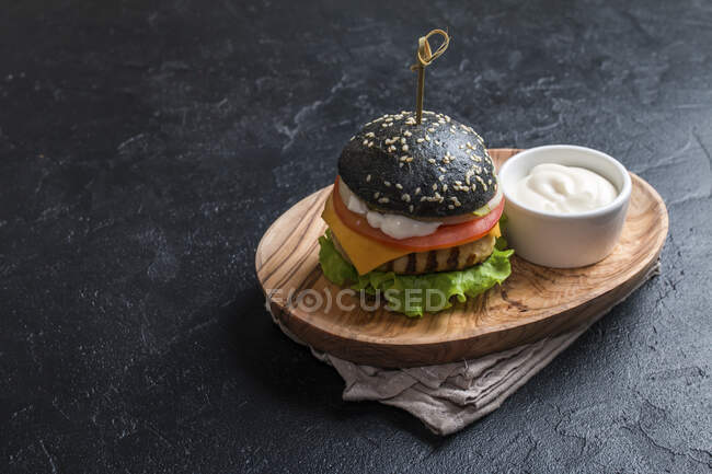 Hamburguesa negra casera con hamburguesa de pollo a la parrilla sobre fondo oscuro - foto de stock