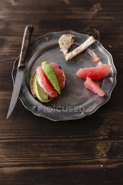 Baguette with avocado and grapefruit on metal tray with knife — Stock Photo