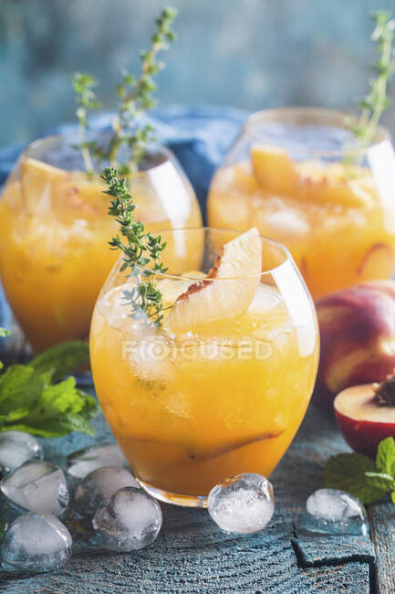 Alcohol Peach cocktails with ice and thyme — Stock Photo