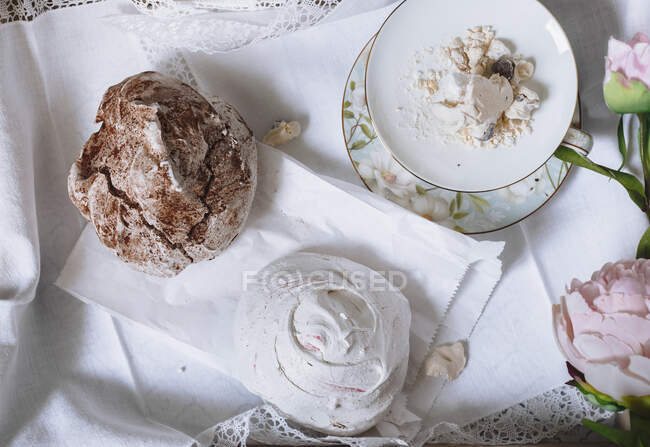 Vista de merengues servidos en mesa con flores - foto de stock