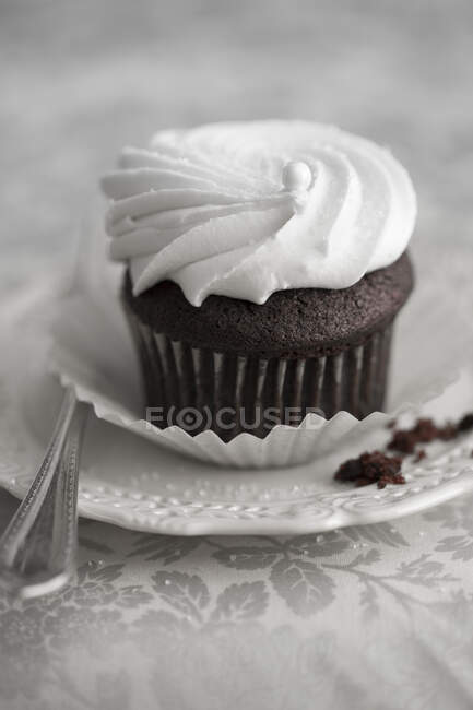 Un cupcake de chocolate cubierto con crema - foto de stock
