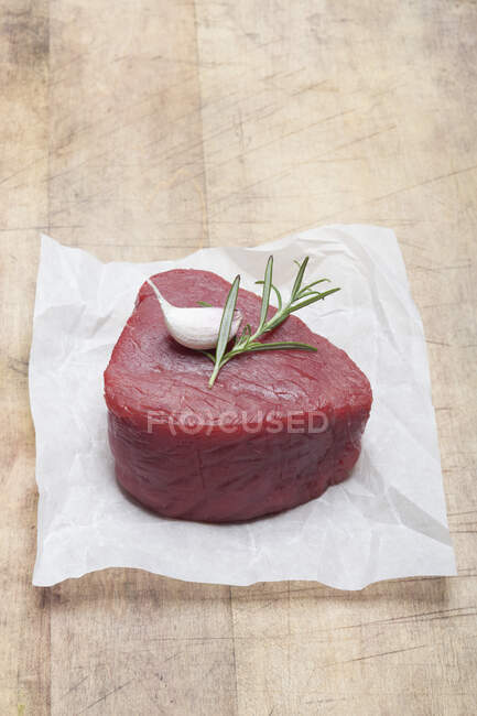A raw fillet of beef with garlic and rosemary — Stock Photo