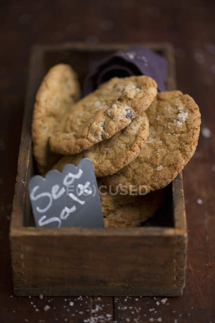 Biscoitos com sal marinho e chocolate em caixa de madeira — Fotografia de Stock