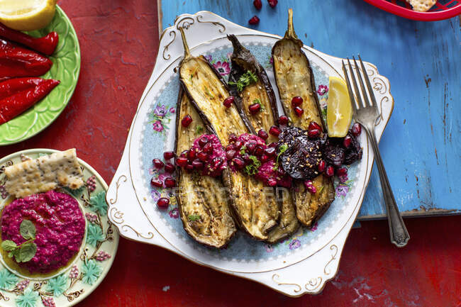 Roasted aubergines with a beetroot and pomegranate sauce and peppermint, and beetroot hummus — Stock Photo